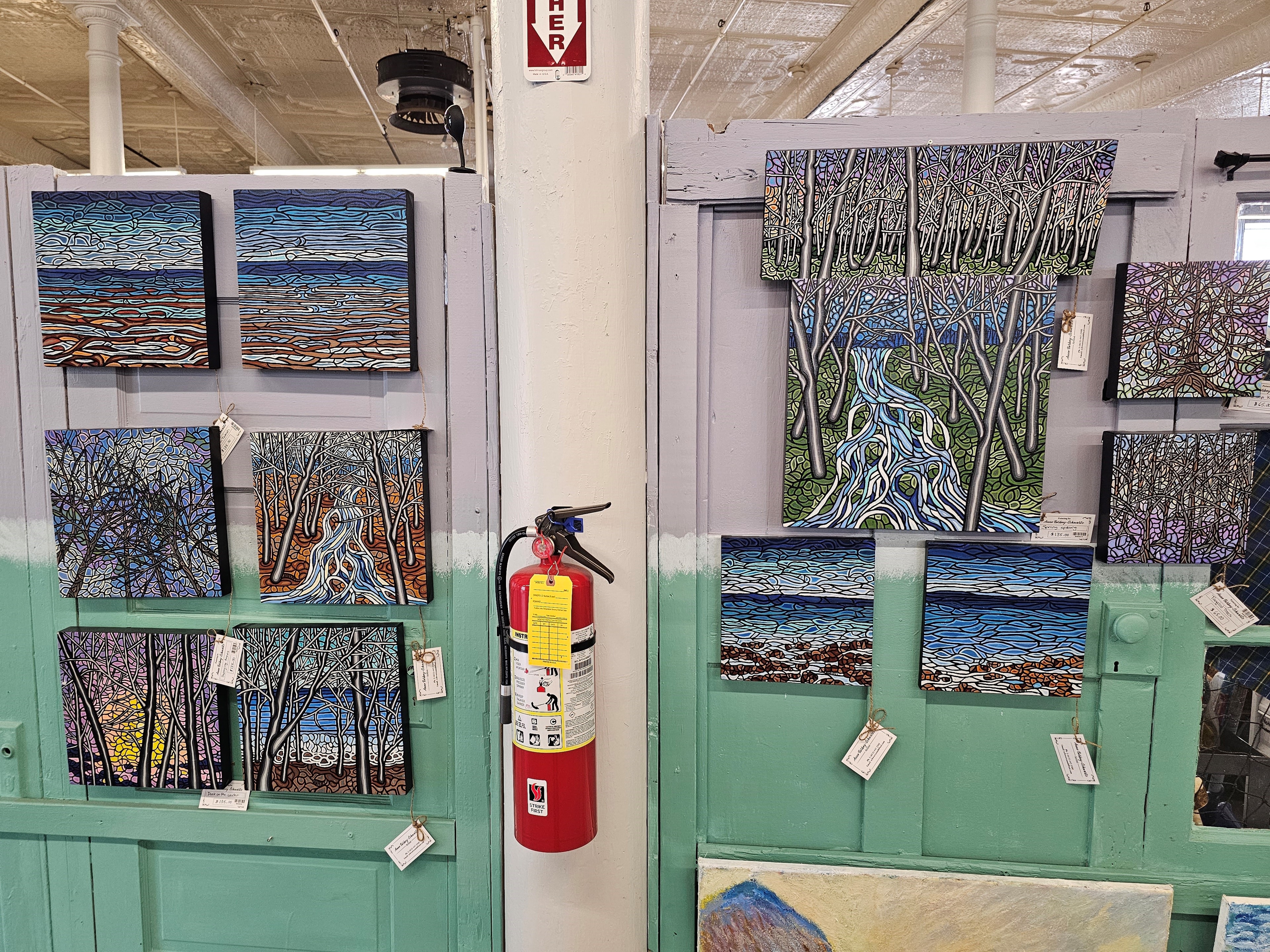 Anne Borbey-Schwartz paintings hung on teal doors at Maritime Mosaic, Amherst NS